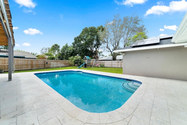 view of pool featuring a lawn, a patio area, and a playground