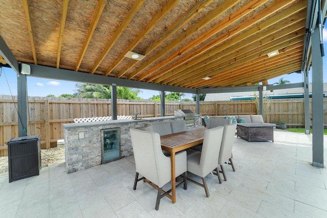 view of patio with an outdoor kitchen, beverage cooler, and a grill