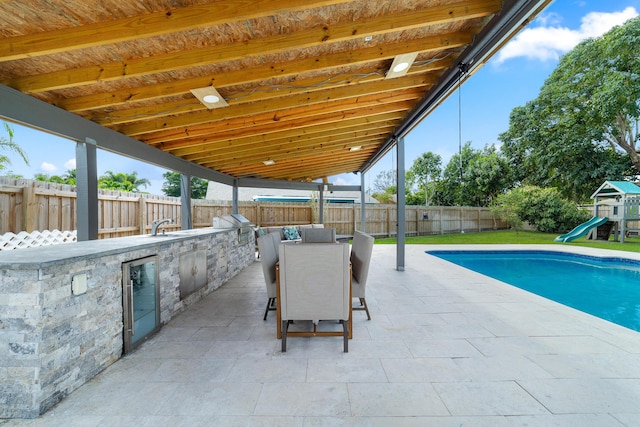 view of patio / terrace with a playground, exterior kitchen, and grilling area