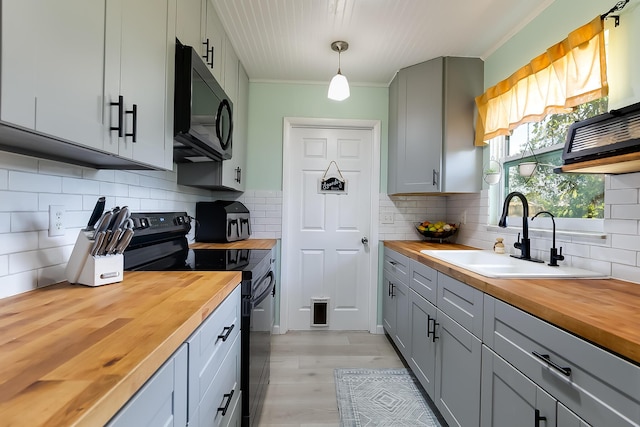 kitchen with wood counters, sink, gray cabinetry, hanging light fixtures, and black appliances