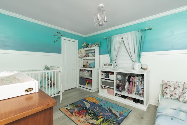 bedroom featuring crown molding, wood-type flooring, and a notable chandelier