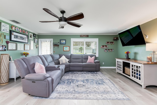 living room featuring crown molding, light hardwood / wood-style flooring, and a healthy amount of sunlight