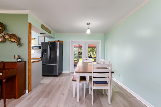 dining space with french doors, ornamental molding, and light hardwood / wood-style floors