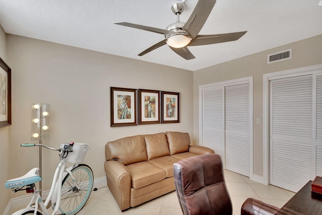 tiled living room featuring ceiling fan and a textured ceiling