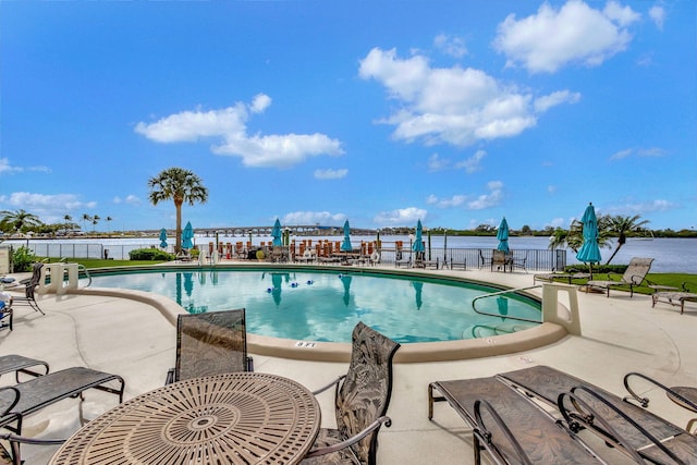 view of pool with a water view and a patio