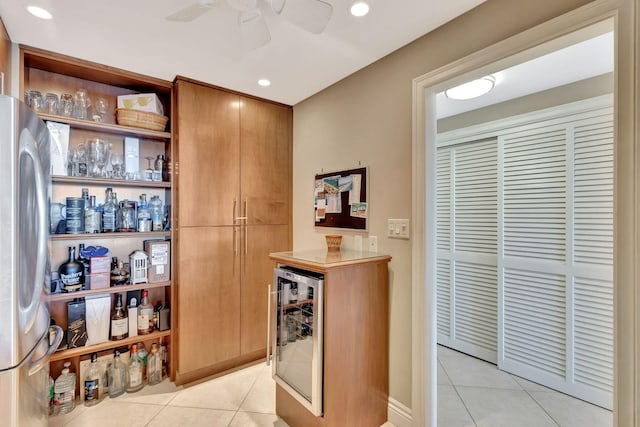 bar featuring beverage cooler, stainless steel refrigerator, ceiling fan, and light tile patterned flooring