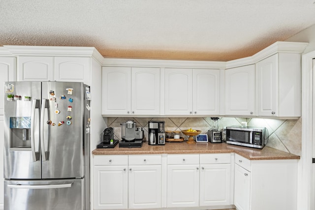 kitchen featuring a textured ceiling, white cabinets, tasteful backsplash, and stainless steel appliances