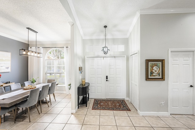 tiled entrance foyer featuring a textured ceiling, ornamental molding, and a notable chandelier