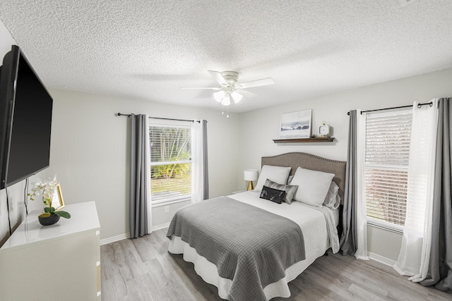 bedroom featuring ceiling fan, a textured ceiling, and light wood-type flooring