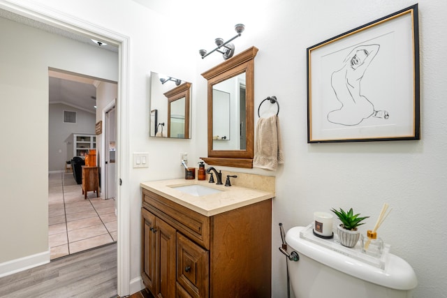 bathroom with wood-type flooring, toilet, vaulted ceiling, and vanity