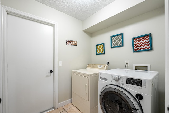 laundry area with a textured ceiling, light tile patterned floors, and independent washer and dryer