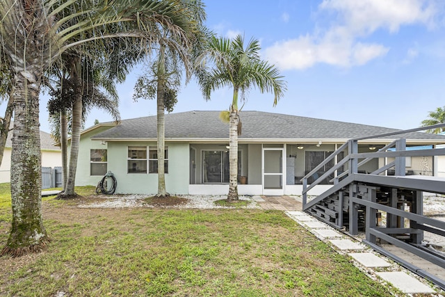 back of house featuring a sunroom and a lawn