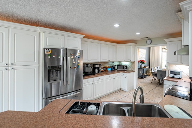 kitchen featuring sink, white cabinetry, light tile patterned floors, decorative backsplash, and stainless steel appliances