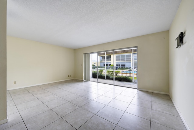 empty room with tile patterned floors, baseboards, and a textured ceiling