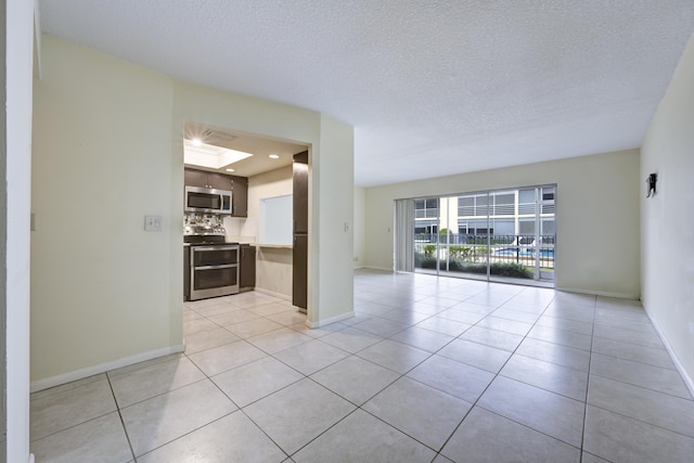 unfurnished room with light tile patterned flooring, a skylight, and a textured ceiling