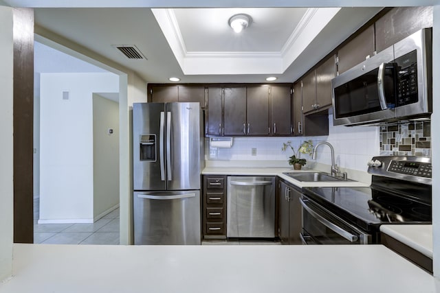 kitchen featuring sink, ornamental molding, appliances with stainless steel finishes, a raised ceiling, and decorative backsplash