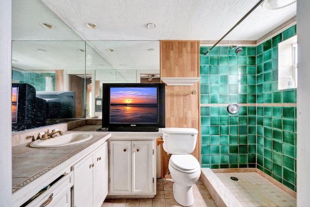 bathroom with tiled shower, vanity, toilet, and tile patterned flooring