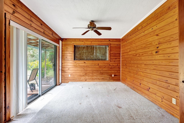 carpeted empty room featuring ceiling fan and wood walls