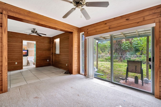 empty room with light tile patterned floors, ceiling fan, and wood walls