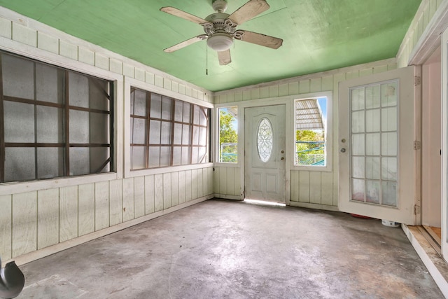 entryway with concrete flooring, ceiling fan, and wood walls