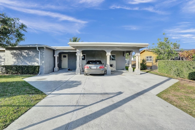 ranch-style house with stucco siding, concrete driveway, fence, a carport, and a front lawn