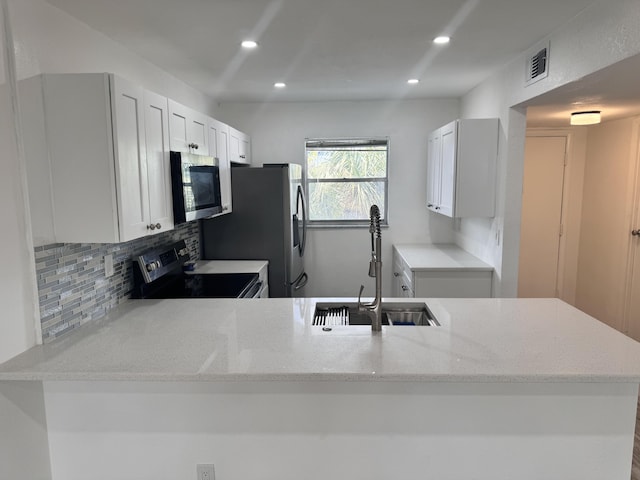 kitchen featuring white cabinets, sink, kitchen peninsula, black electric range, and light stone counters