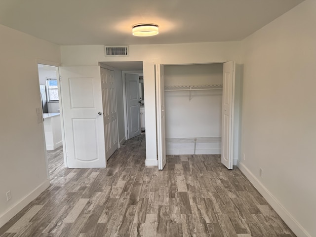 unfurnished bedroom with a closet, dark hardwood / wood-style floors, and stainless steel refrigerator