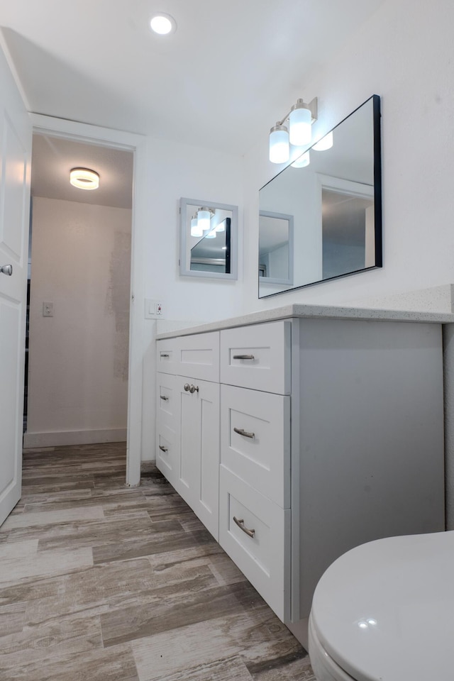 bathroom with toilet, wood-type flooring, and vanity