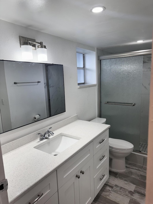 bathroom with an enclosed shower, vanity, toilet, and hardwood / wood-style flooring