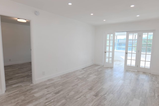 empty room featuring french doors and light hardwood / wood-style flooring