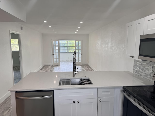 kitchen featuring light hardwood / wood-style floors, appliances with stainless steel finishes, tasteful backsplash, white cabinets, and sink