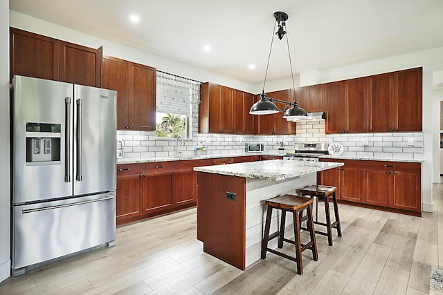 kitchen with decorative backsplash, light wood-style flooring, appliances with stainless steel finishes, and a kitchen island