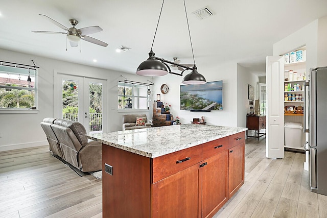 kitchen featuring visible vents, light wood-type flooring, freestanding refrigerator, and open floor plan