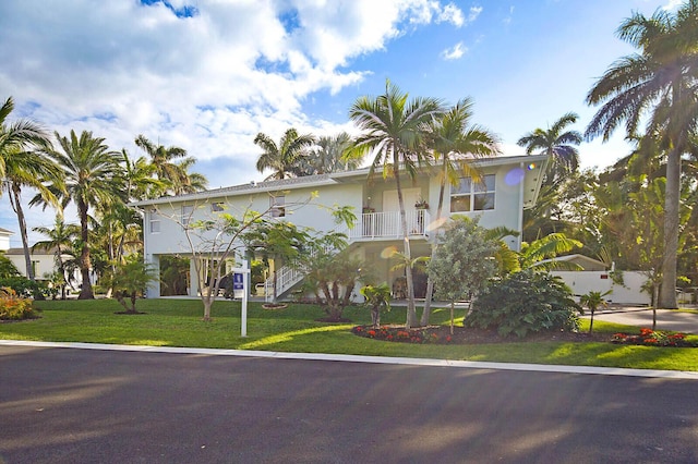 view of front of home featuring a balcony and a front lawn