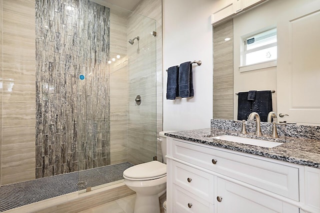 bathroom with vanity, tiled shower, tile patterned floors, and toilet