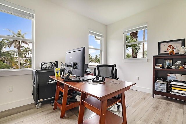 home office with a wealth of natural light and light hardwood / wood-style floors