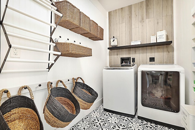 clothes washing area featuring washing machine and clothes dryer and wooden walls