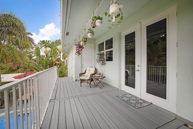 wooden terrace featuring an outdoor pool and french doors