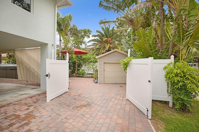 view of patio / terrace with an outbuilding, a gate, fence, and a storage unit