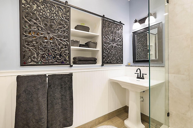 bathroom with a wainscoted wall and a shower