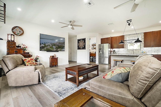 living room featuring ceiling fan, sink, and light wood-type flooring