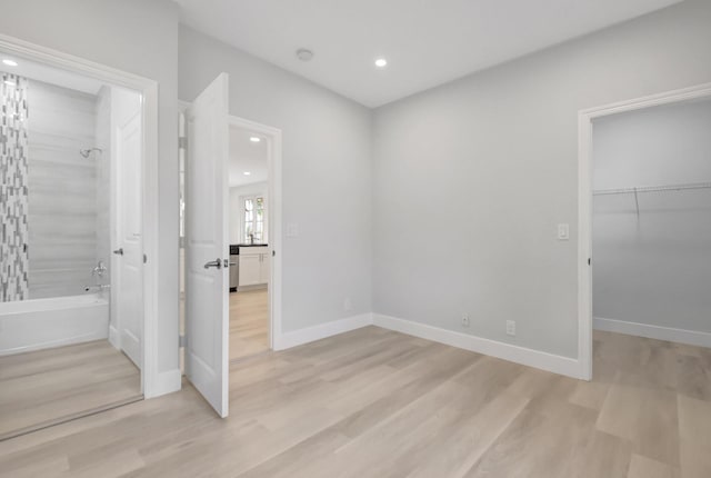 unfurnished bedroom featuring a walk in closet, light hardwood / wood-style floors, and a closet