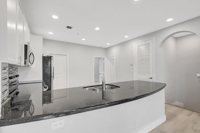 kitchen featuring sink, kitchen peninsula, white cabinets, and appliances with stainless steel finishes