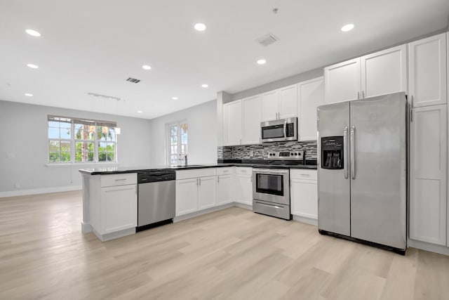 kitchen with white cabinetry, appliances with stainless steel finishes, decorative light fixtures, and kitchen peninsula