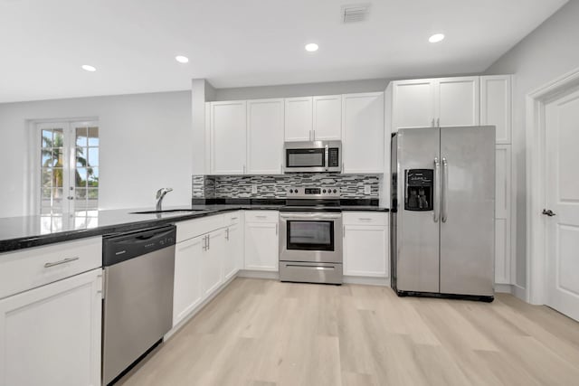 kitchen featuring sink, appliances with stainless steel finishes, white cabinets, decorative backsplash, and light wood-type flooring