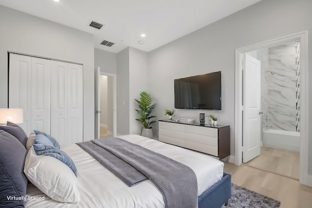 bedroom featuring connected bathroom, a closet, and light wood-type flooring