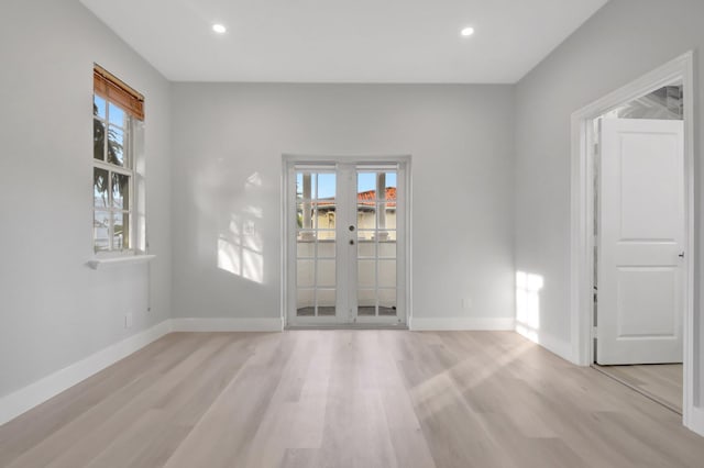 empty room with light hardwood / wood-style floors and french doors