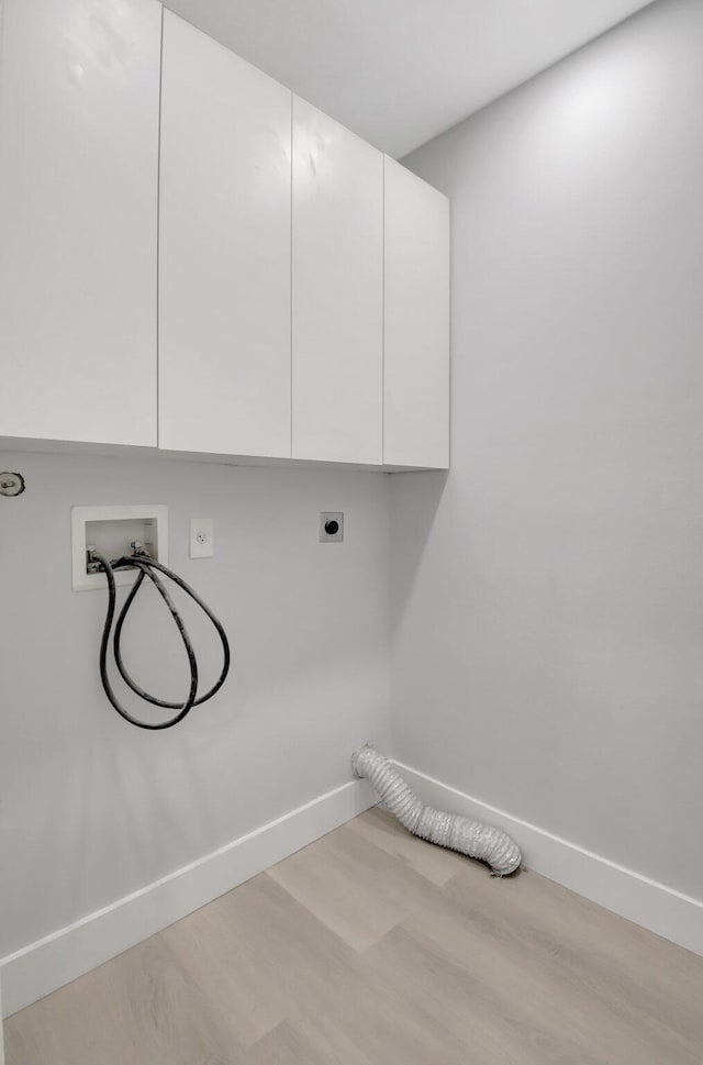 laundry room with electric dryer hookup, washer hookup, cabinets, and light wood-type flooring