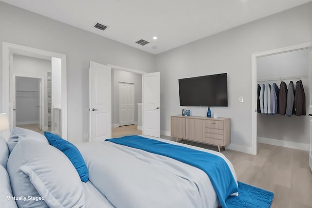 bedroom featuring a spacious closet, light wood-type flooring, and a closet