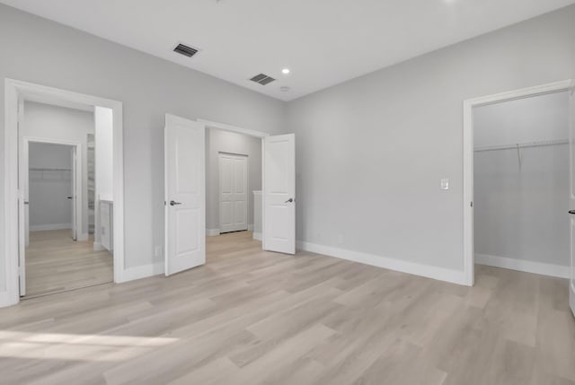 unfurnished bedroom with a spacious closet, light hardwood / wood-style floors, and a closet